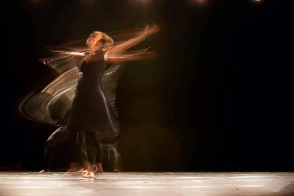 Meisner's outward attention: a dancer turning on a dark stage, blurred with movement