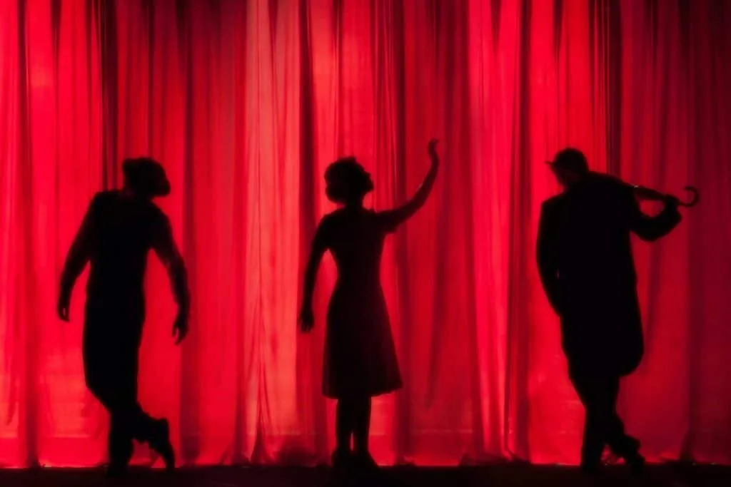 Stanislavski's emotion memory: three actors in silhouette on a stage in front of a red curtain