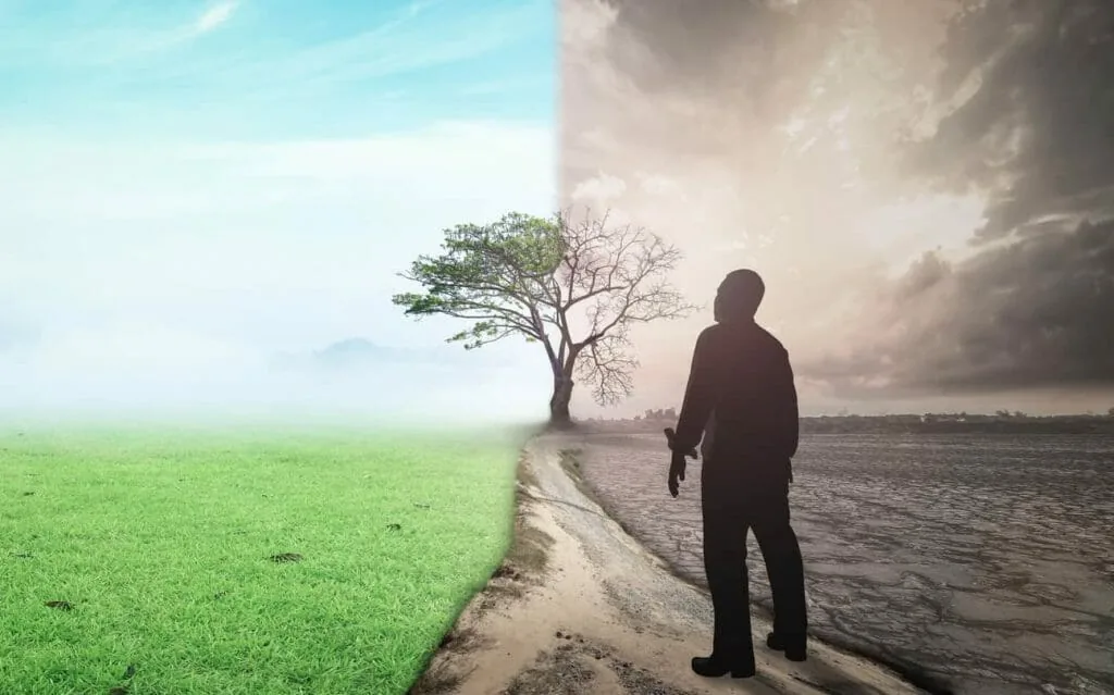 Trade scarcity for abundance: a man in silhouette standing between a green field and cracked dry land under storm clouds