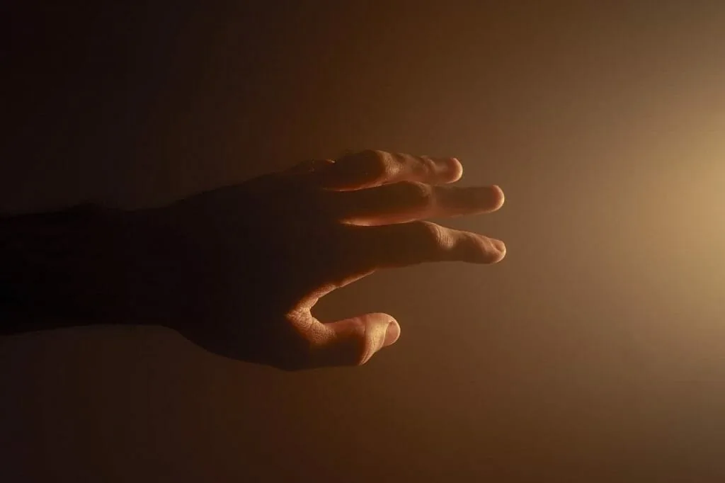 Asking for one specific thing: a hand reaches out towards a soft, warm light in the dark