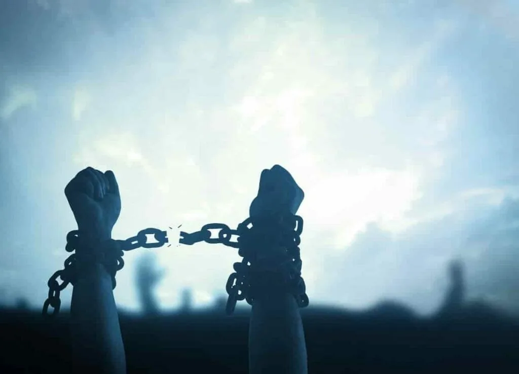 How to stop living vicariously: two raised fists breaking a chain against a pale sky