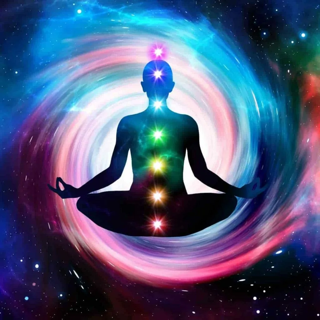 What are chakras: the 7 chakras shown as glowing points of light along the spine of a person meditating cross-legged in a swirl of starry sky