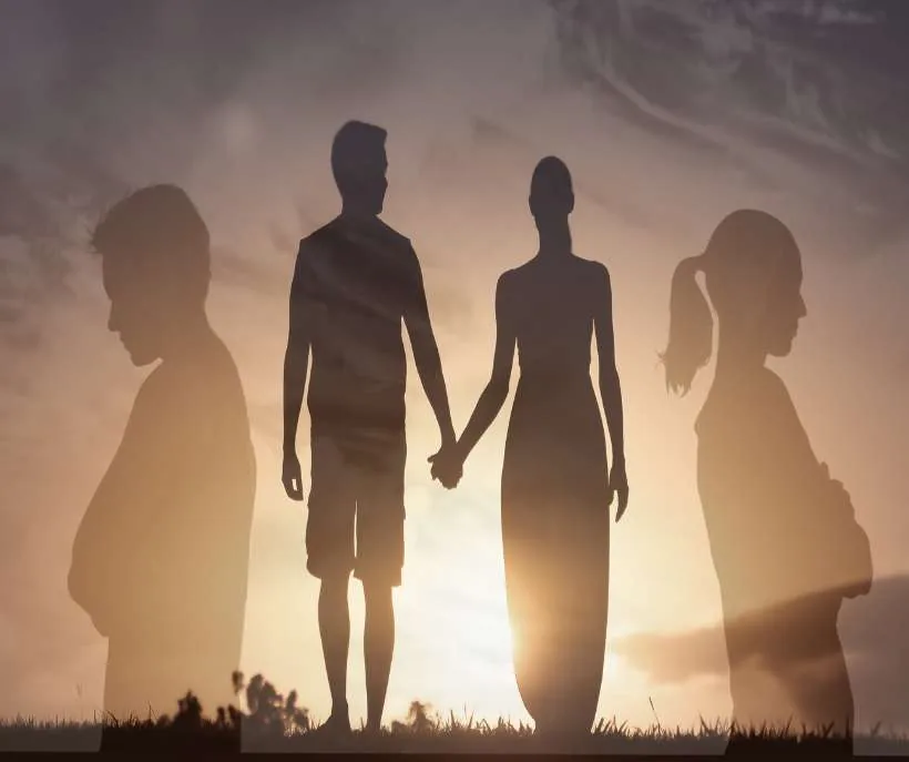 5206 angel number meaning in love: a couple holding hands at sunset between two faded figures turning away from each other