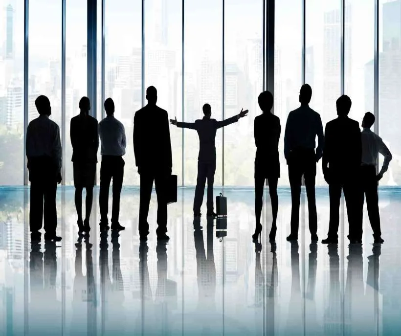 7482 angel number meaning in work and money: colleagues in silhouette at tall office windows, one in the middle with arms raised