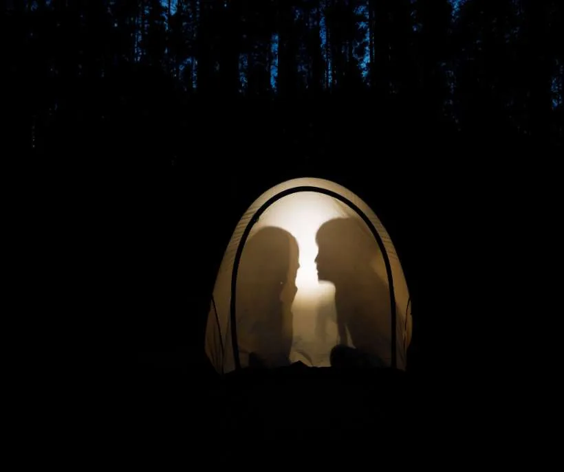 What is the whisper method: two silhouettes face each other inside a glowing tent in a dark forest at night